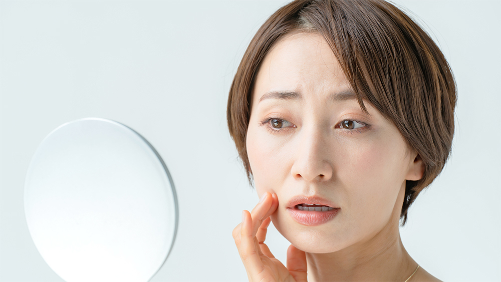 鏡を見て理想の口元をイメージする40代女性